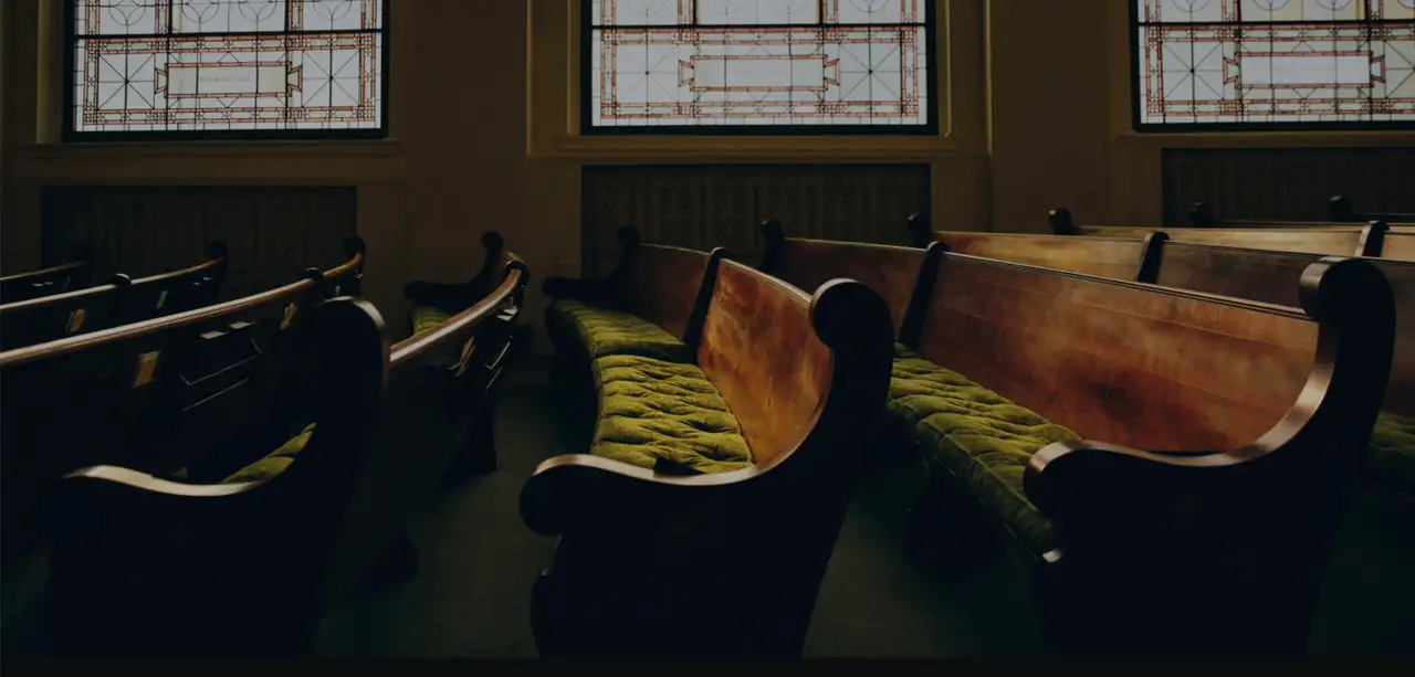 Wooden church pews beneath tall windows